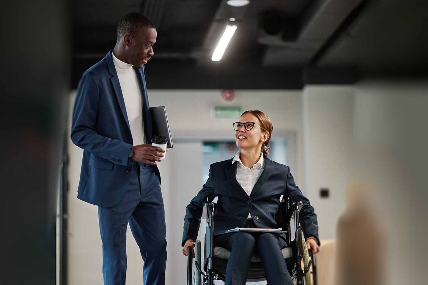 Businessman chatting with female executive in wheelchair working abroad