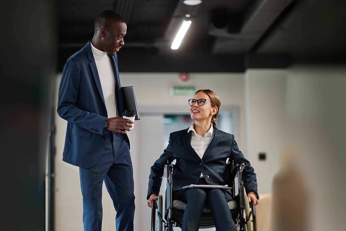 Businessman chatting with female executive in wheelchair working abroad