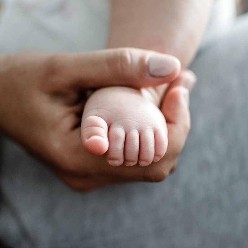 Parent holding new-born baby's foot